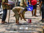 Markers on the floors like the ones municipal workers are painting outside a store in India can help people keep their social distance even as public spaces reopen.