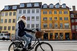 A cyclist rides her bicycle past residential and commercial properties in the Christianshavn district of central Copenhagen.
