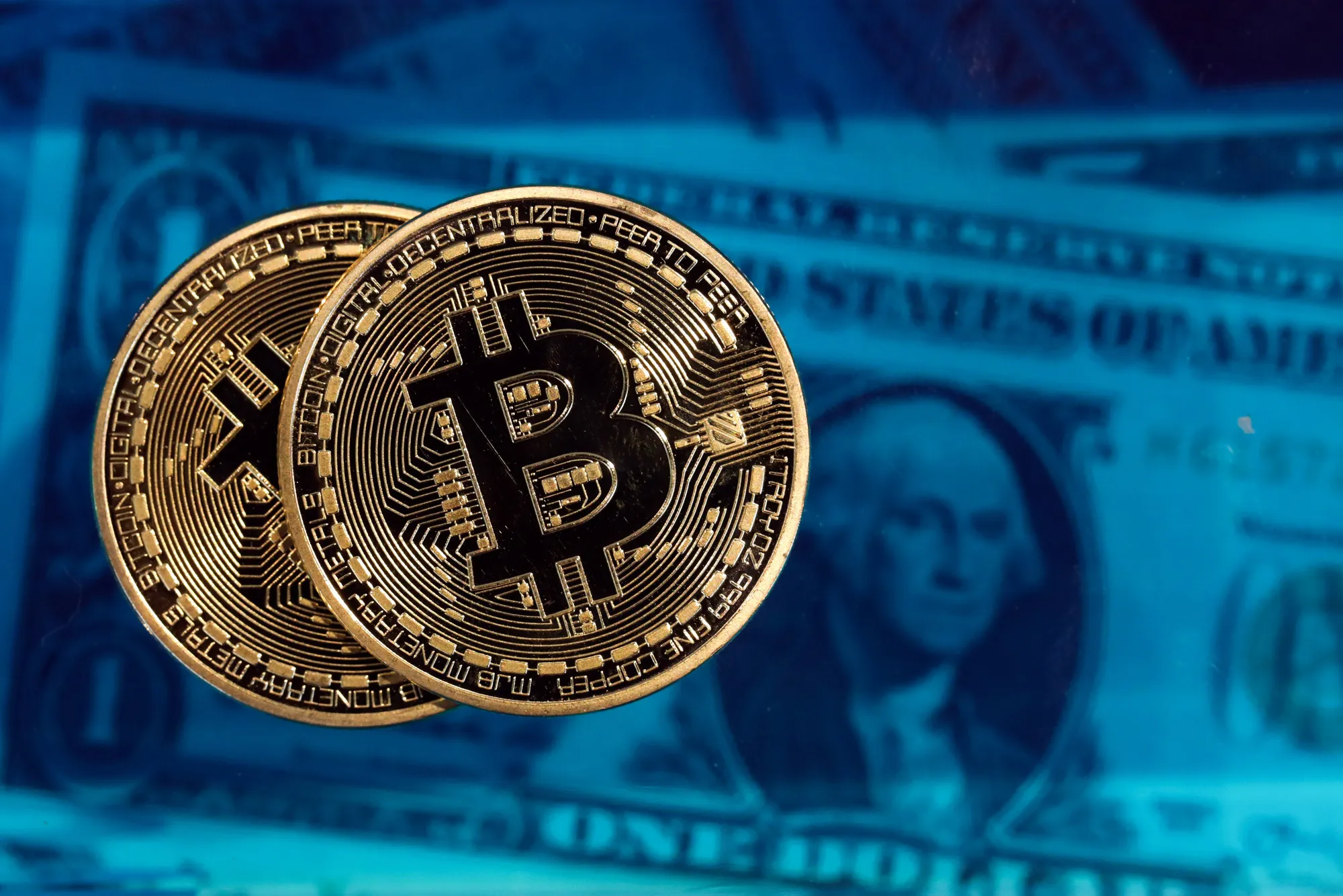 Bitcoin tokens sit next to a collection of U.S. one dollar bills
