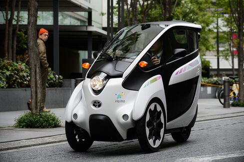 A Park24 employee drives a Toyota i-Road electric personal mobility vehicle along a street in Tokyo.