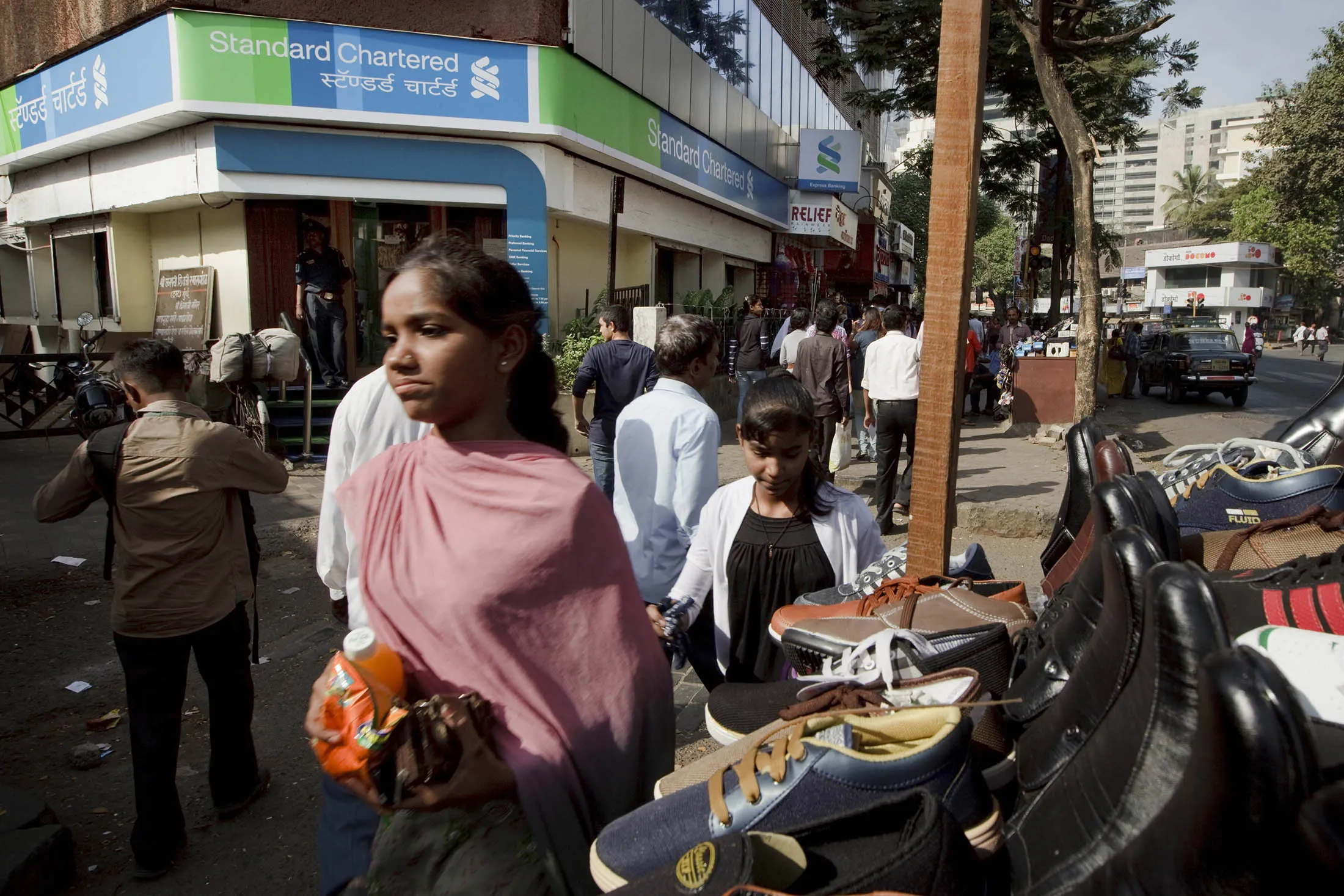 Pedestrians walk by a Standard Chartered bank in Mumbai.

