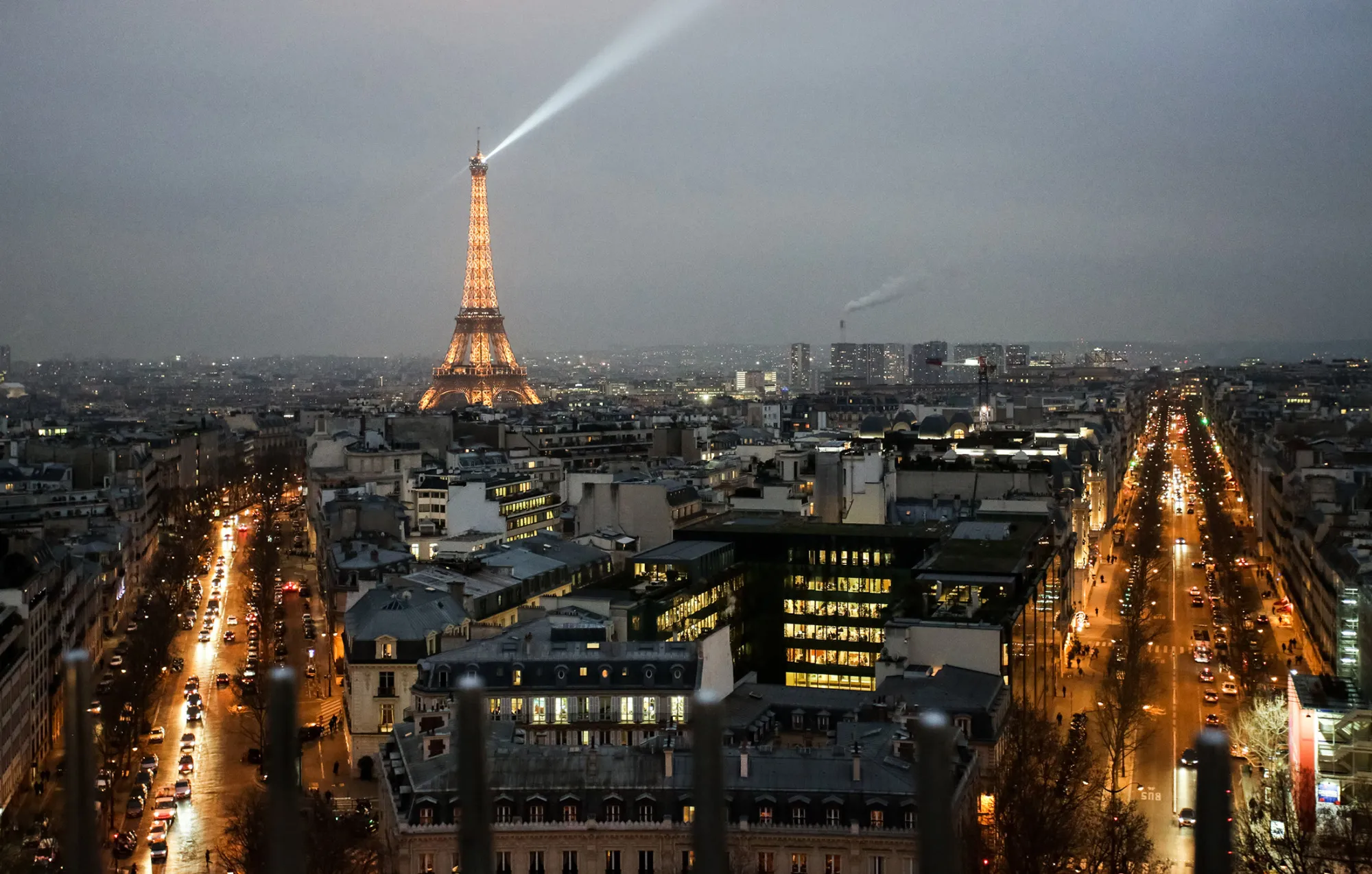 The Eiffel Tower stands illuminated on the city skyline at dusk in Paris.
