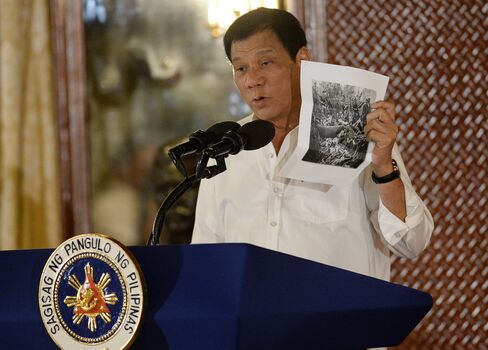 President Rodrigo Duterte holds up a photo, citing accounts of US troops who have killed Muslims during the US occupation of the Philippines in the early-1900s during a speech at the oath-taking of newly appointed government officials, at Malacanang palace in Manila on Sept. 12.