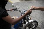 A customer pays a mobile mechanic in U.S. banknotes in Caracas on April 25.