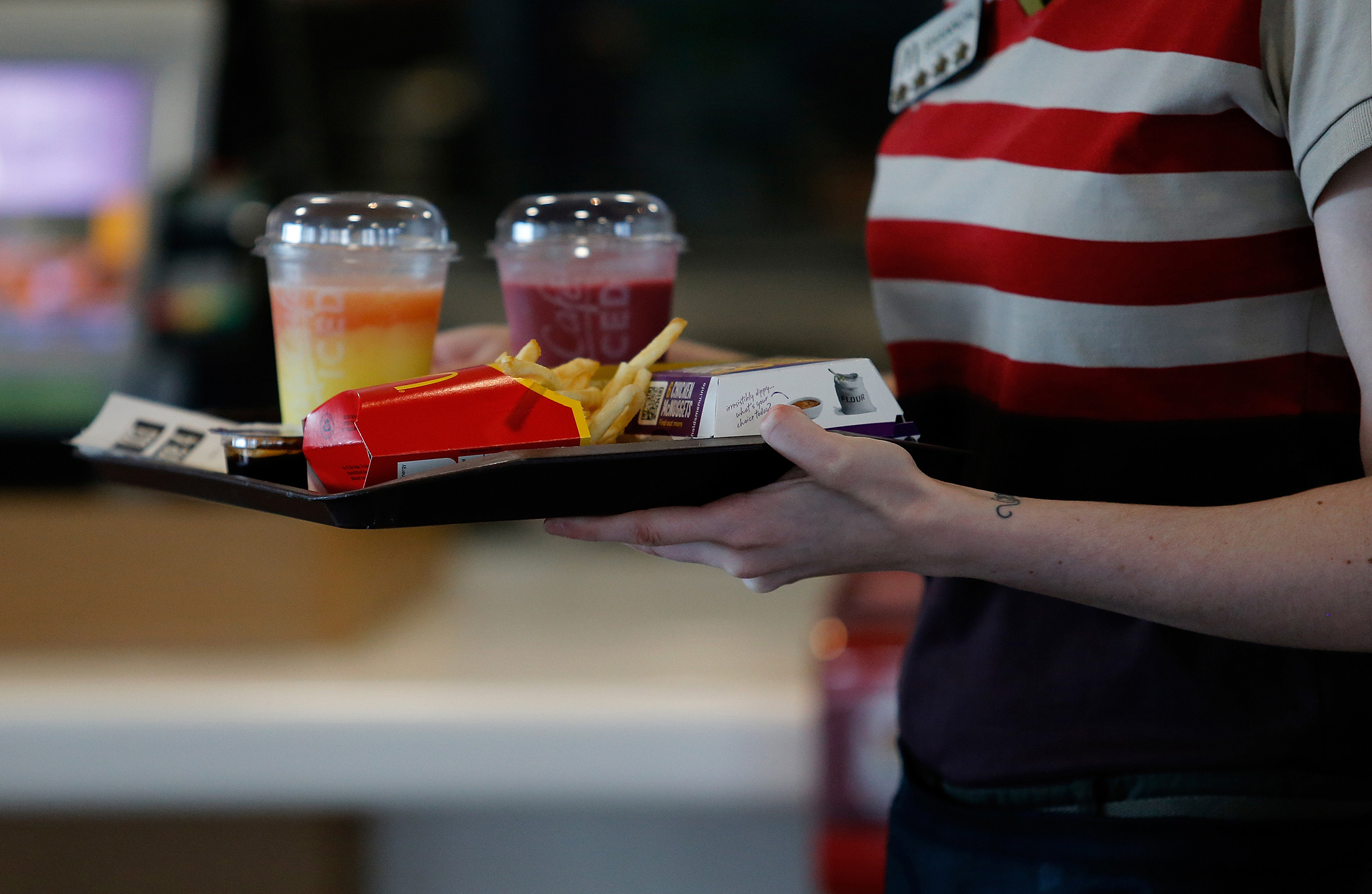 An employee delivers a tray of food and beverages to a customer's table inside a McDonald's Corp. restaurant in Manchester, U.K.
