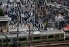 A East Japan Railway Co. (JR East) train moves on an elevated track as pedestrians cross an intersection in the Shibuya district of Tokyo, Japan, on Friday, March 31, 2017. The yen weakened against the dollar last month by the most since 1995. A moderate recovery is underway, with the economy growing for the first nine months of the year.