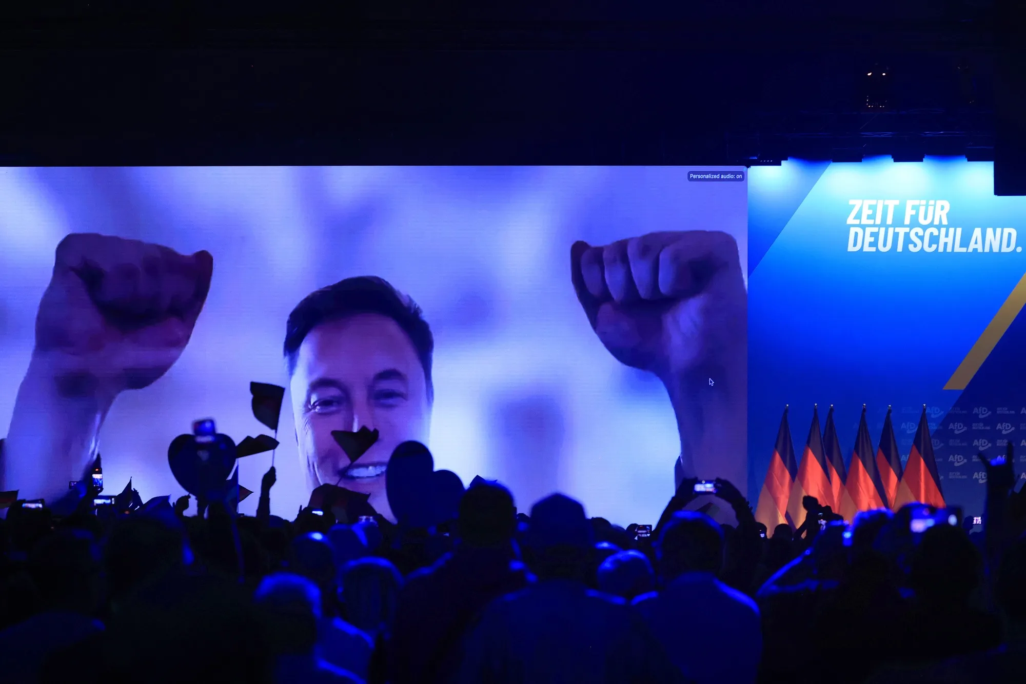 Elon Musk raises his fists as he speaks virtually during the Alternative for Germany (AfD) general election campaign launch in Halle, Germany, on Jan. 25, 2025.