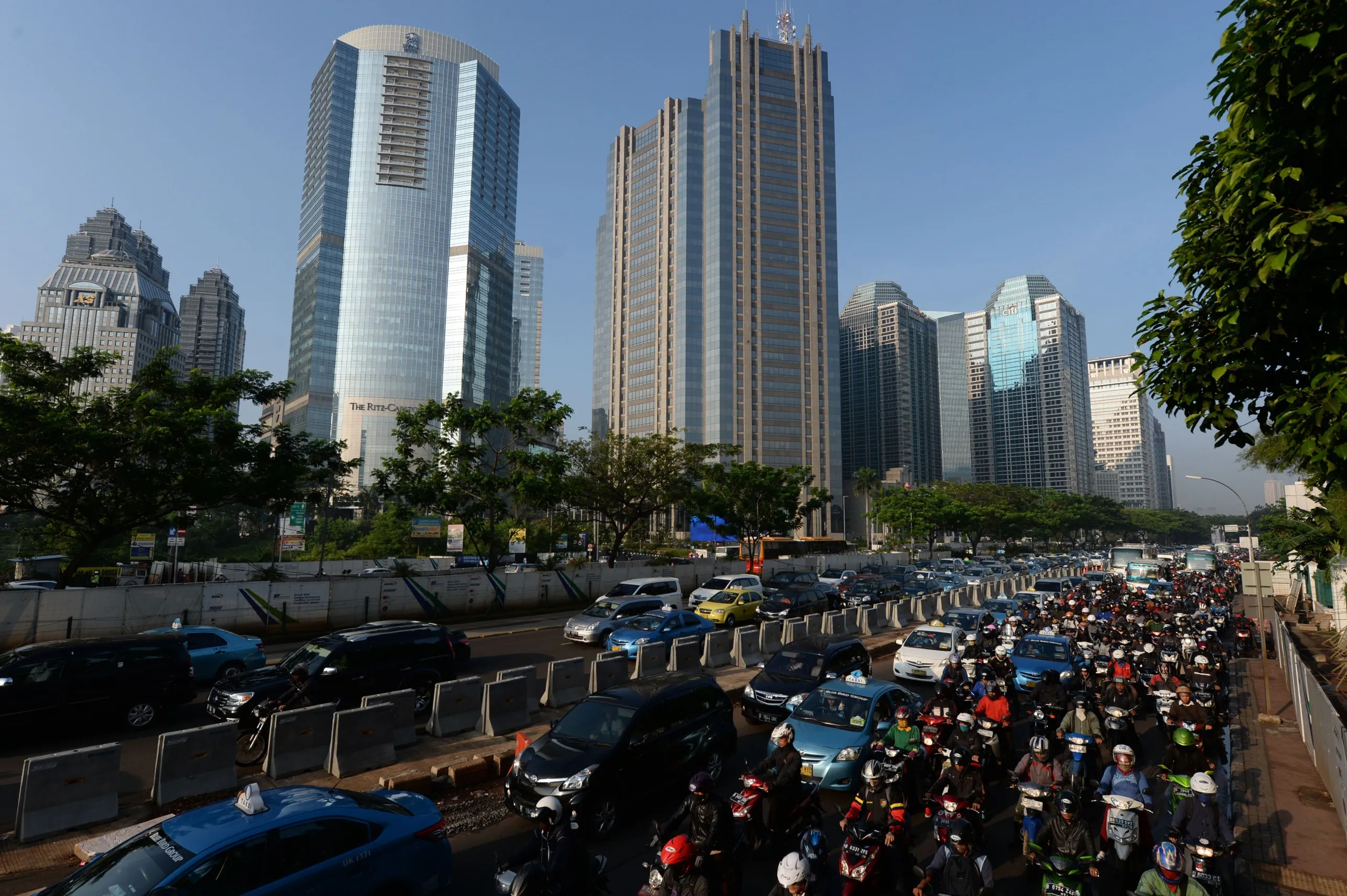 Cars and motorcycles sit in congested traffic while driving past commercial buildings in the business district in Jakarta.