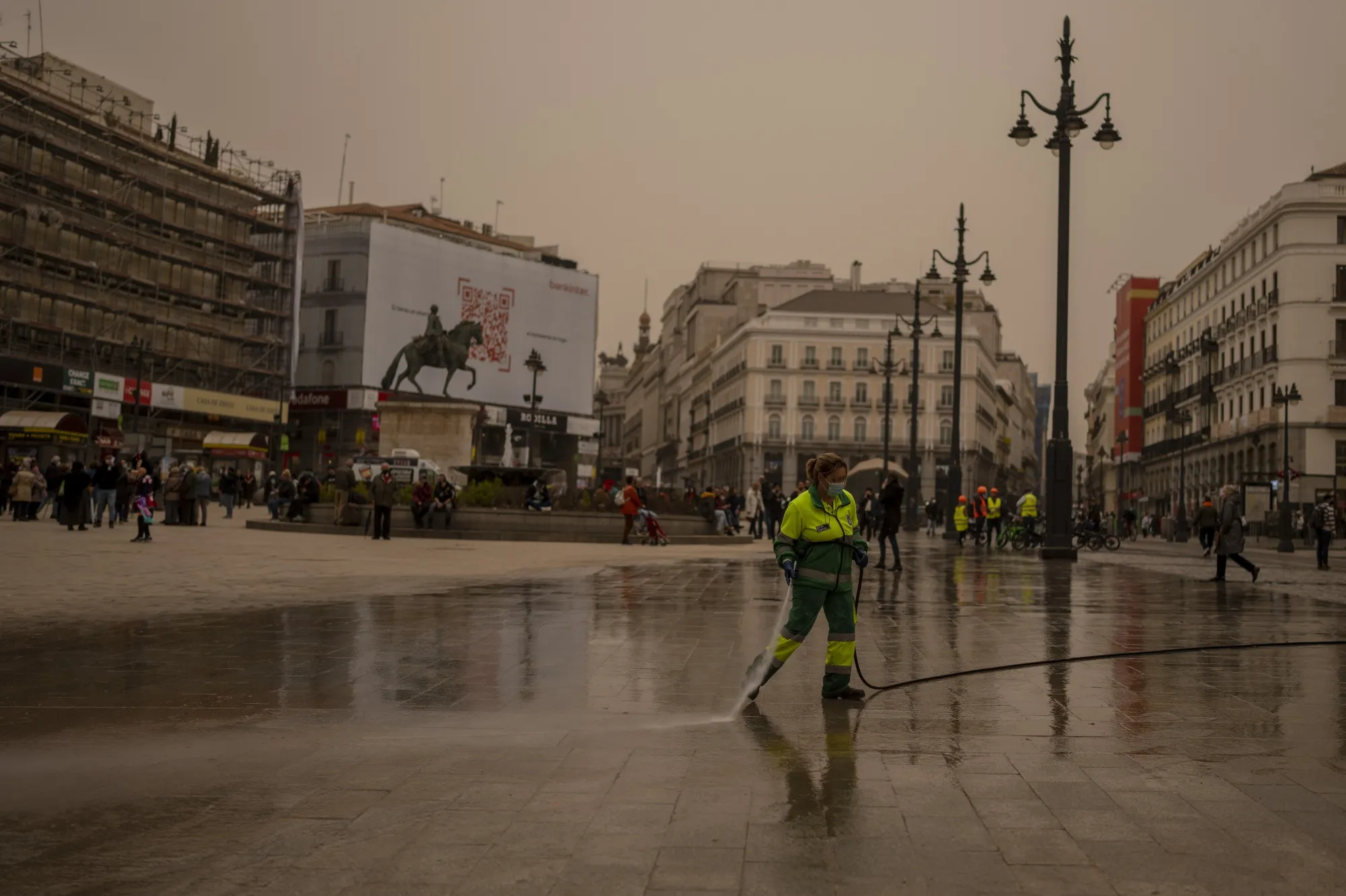 A worker cleans the dust from the Sahara desert at Sol square in Madrid, Spain, Tuesday, March 15, 2022. Spain issued extremely poor air quality ratings for a large swathe of Spain Tuesday, after a mass of hot air from the Sahara dumped loads of dust after crossing the Mediterranean. (AP Photo/Manu Fernandez)