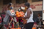 A woman wearing a face mask buys oranges at a market in Lusaka, Zambia.