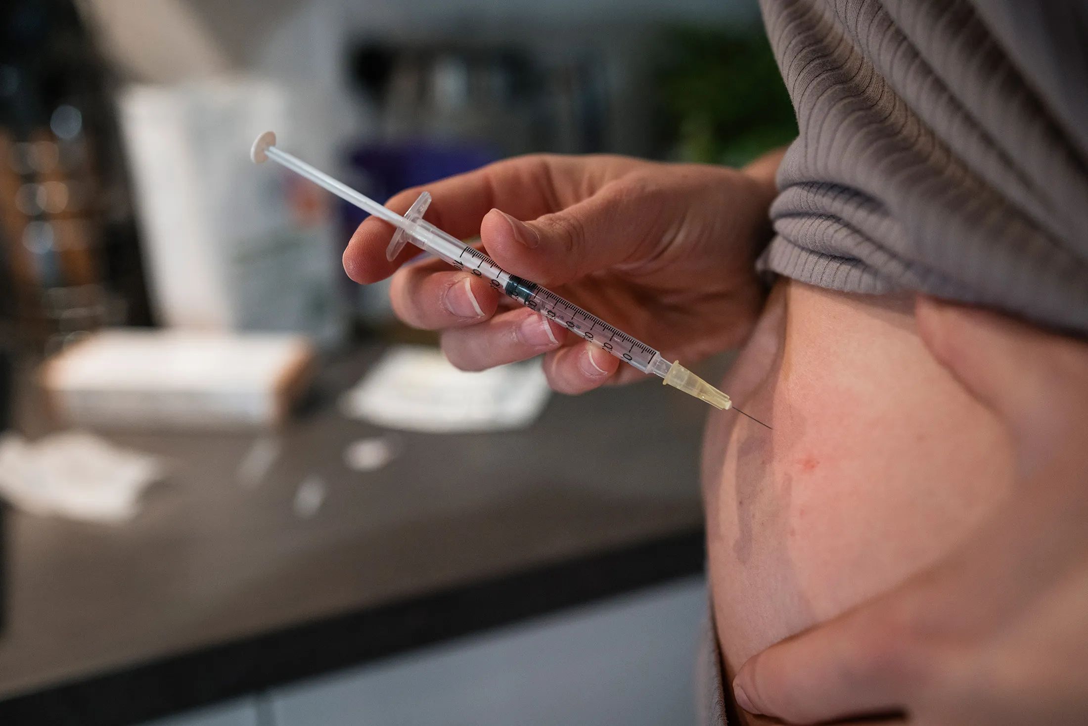 A woman injects herself with a hormone meant to induce superovulation.