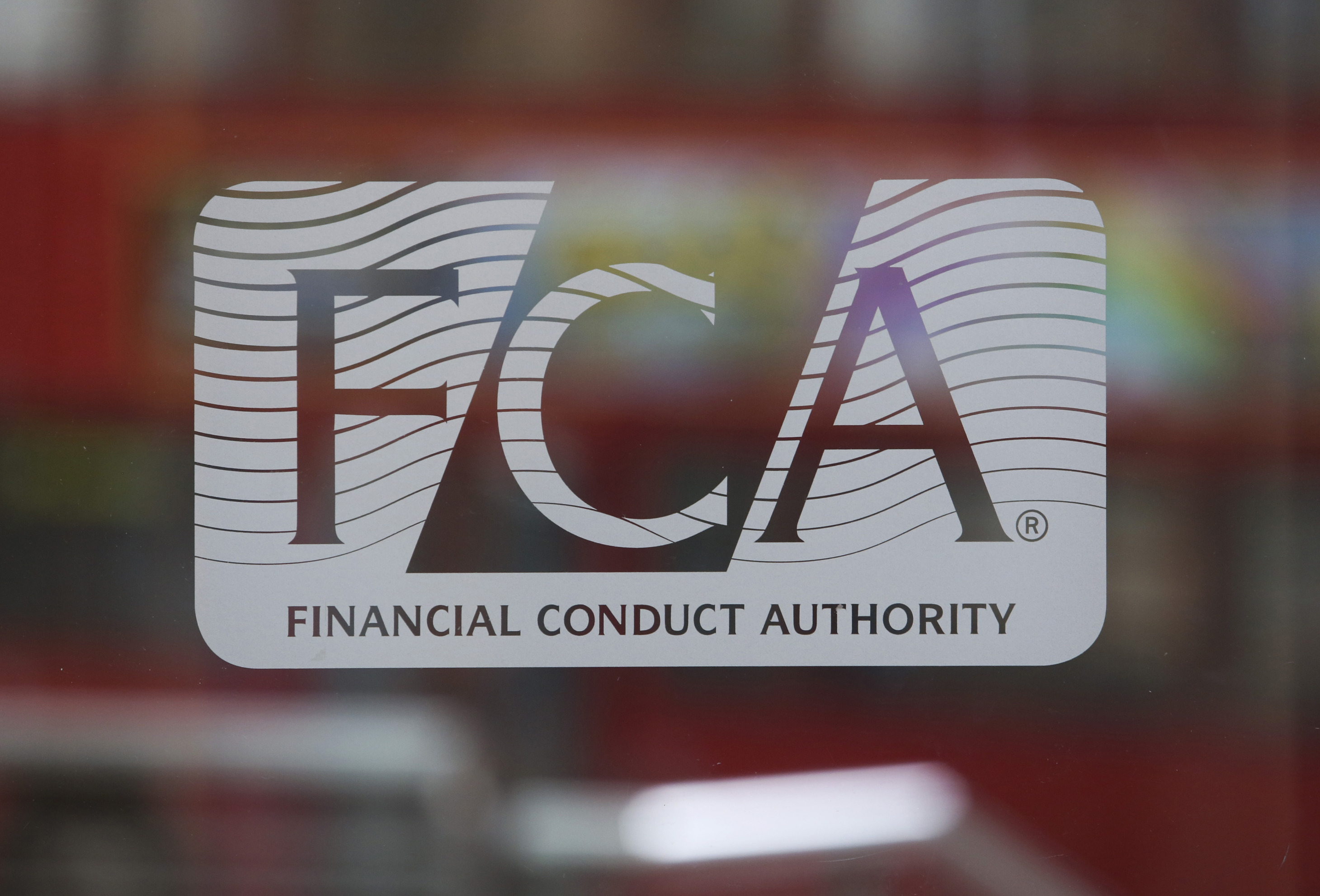 A logo sits on a revolving glass door at the headquarters of the Financial Conduct Authority in London.