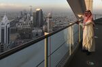 An employee looks out from the 32nd floor viewing platform of the Al Faisaliah Tower, as skyscrapers and commercial buildings stand beyond.