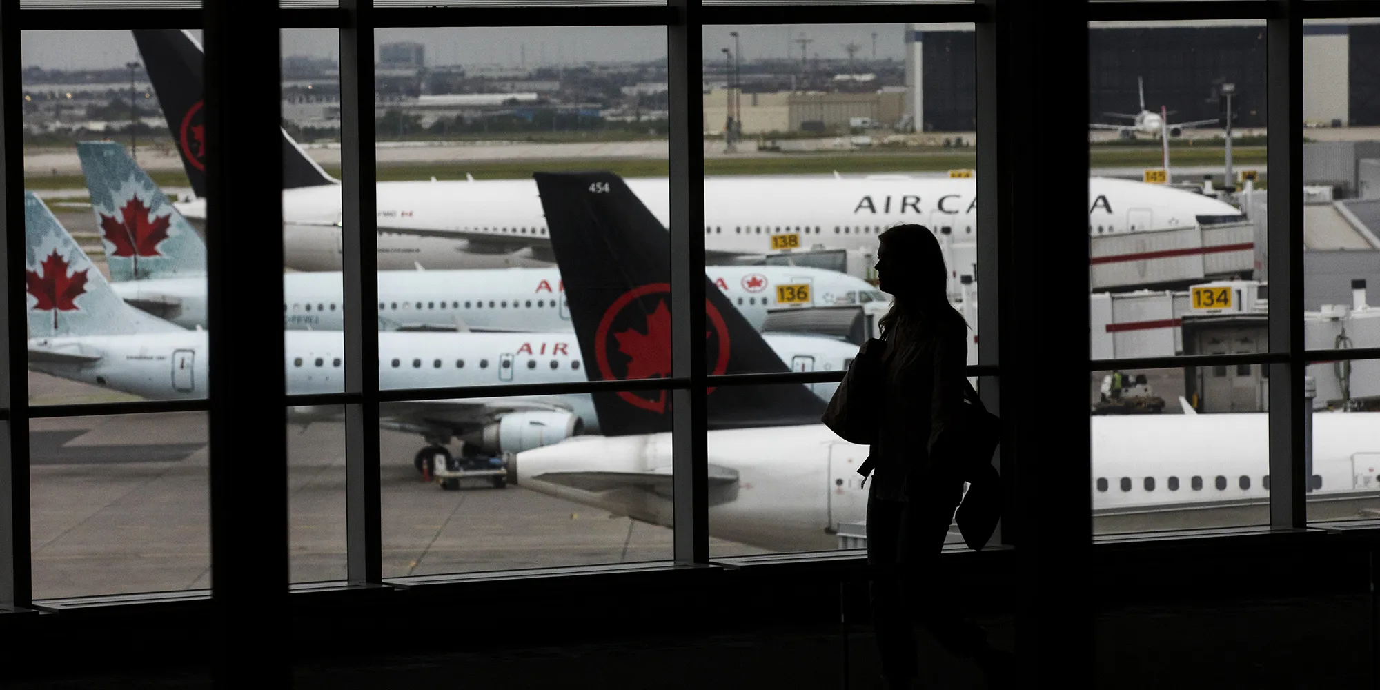 A traveler walks past Air Canada planes at Toronto Pearson International Airport&nbsp;in Toronto.