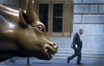 A man walks past the bull statue near the New York Stock Exchange in New York, U.S.