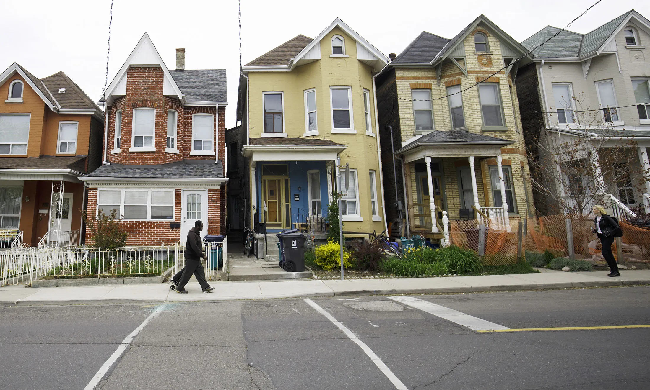 Pedestrians pass in front of houses in Toronto, Ontario, Canada, on Thursday, May 11, 2017. Toronto home prices climbed 5 percent in April, suggesting the Ontario government's foreign buyer tax and troubles at Home Capital Group Inc. haven't yet cooled the market.
