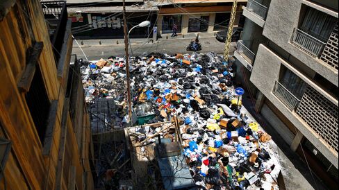 A motorcycle passes by a large pile of garbage blocking a street in Beirut, July 27, 2015. Photographer: Hassan Ammar/AP Photo