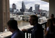 Visitors look out at the skyline from the terrace of Switch House, part of the Tate Modern art gallery, as skyscrapers including the Leadenhall building, also known as the "Cheesegrater", center and 20 Fenchurch Street, also known as the "Walkie-Talkie", right, stand beyond, in London, U.K., on Tuesday, June 28, 2016. Banks demand for cash surged at the Bank of Englands first liquidity operation since the U.K. voted to leave the European Union, with financial institutions requesting more than double the amount allocated. Photographer: Simon Dawson/Bloomberg