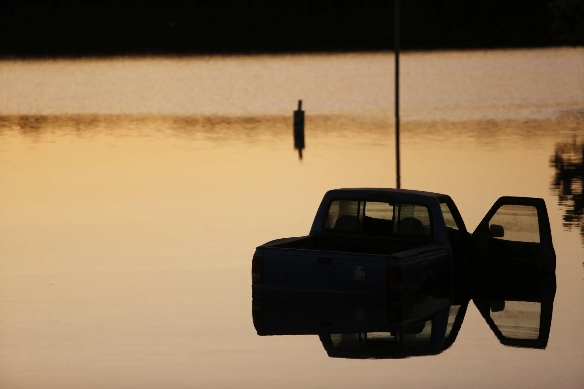 The silhouette of a truck is seen submerged in water at a trailer park flooded by Hurricane Harvey in Rose City, Texas, on&nbsp;Sept. 6. Disaster is fueling a growth industry as more frequent and powerful storms lash coastal regions teeming with new homes and offices.