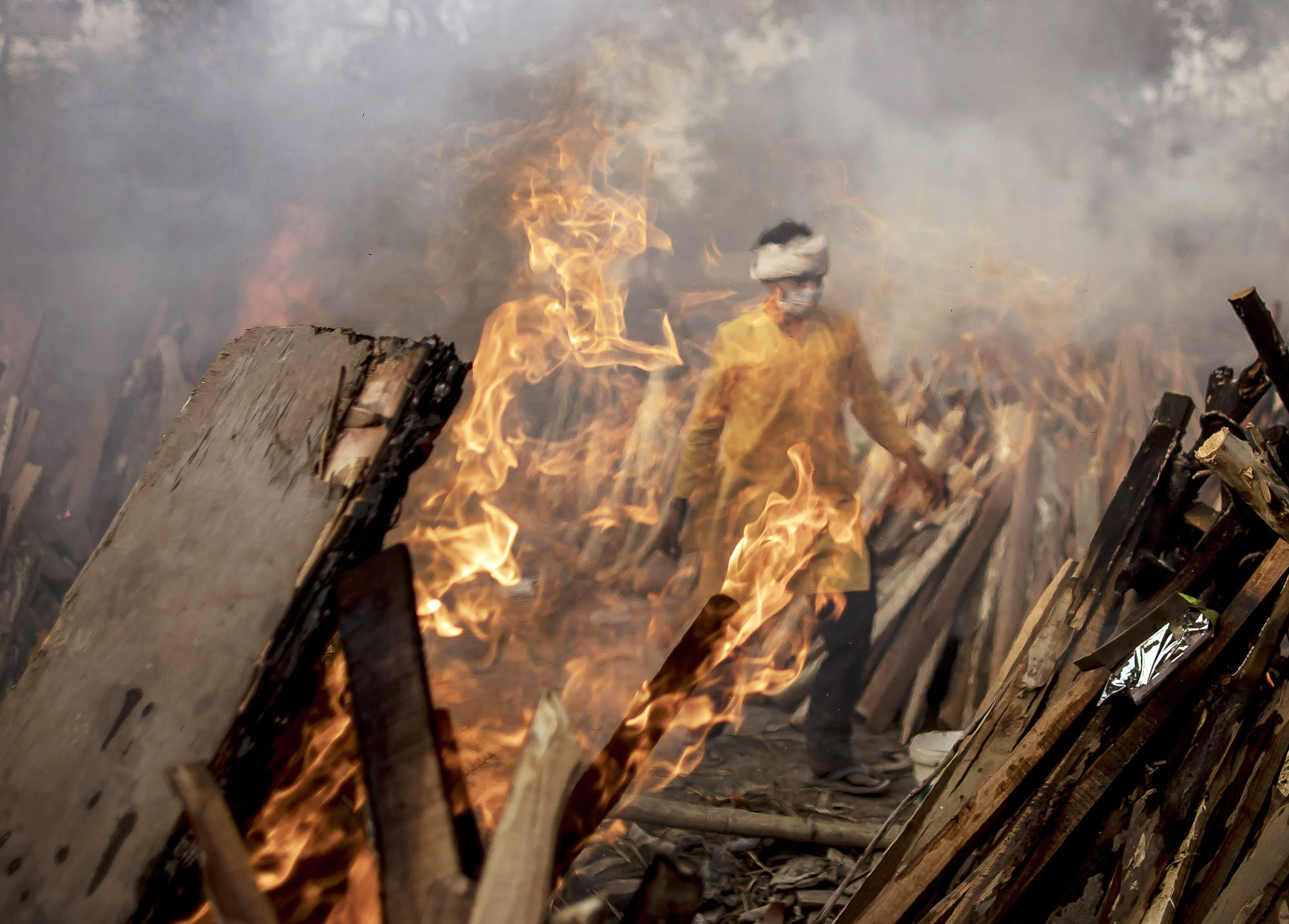 A priest walks near&nbsp;burning funeral pyres&nbsp;in New Delhi, India on May 1.
