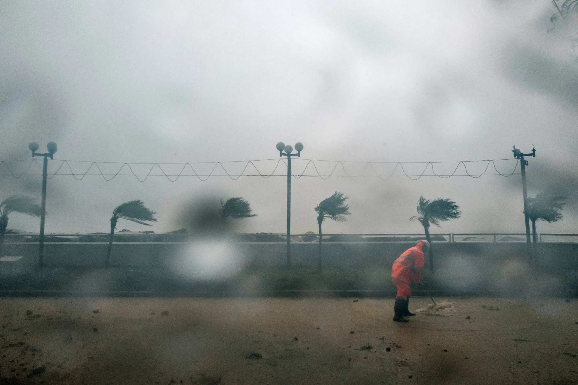 A worker clears debris at a promenade during a No. 9 Storm Signal in Hong Kong