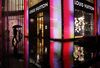 A man holding an umbrella walks past a Louis Vuitton store, operated by LVMH Moet Hennessy Louis Vuitton SA, in Shanghai, China.