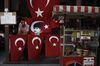 A man uses a mobile phone beside a street vendor's display of Turkish flags and an image of Kemal Ataturk, founder of the Turkish republic, in the Sultanahmet district of Istanbul, Turkey, on Thursday, Aug. 3, 2017. Turkey’s central bank raised its inflation forecast for this year on higher food prices, and reiterated its policy not to loosen monetary conditions until the outlook improves.