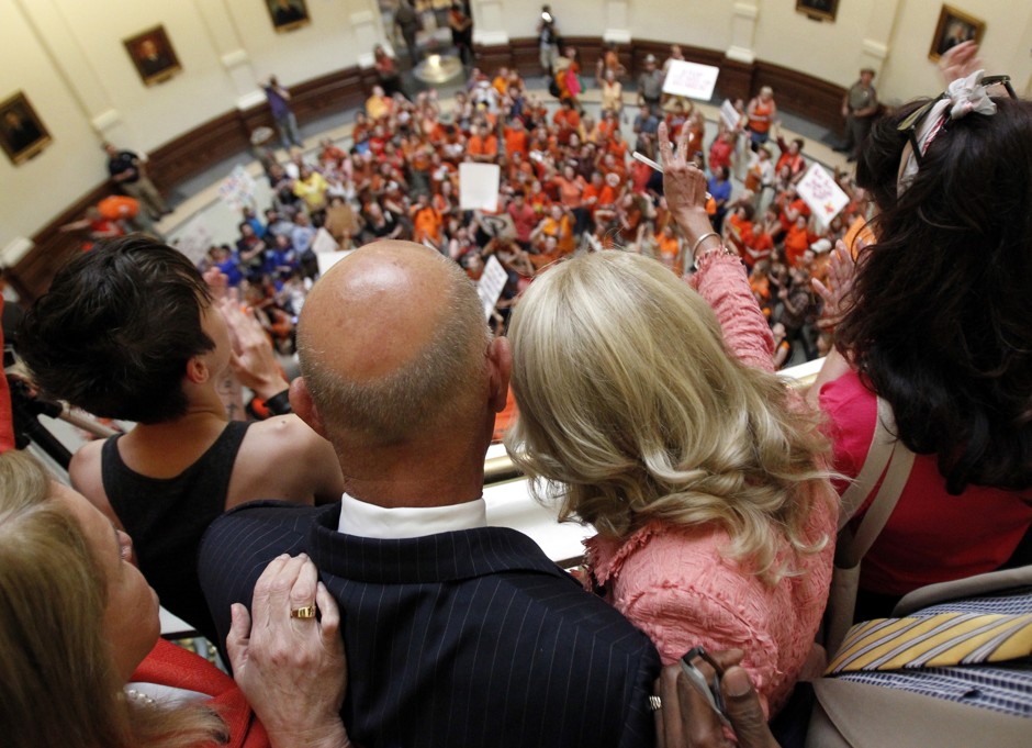 Texas State Senators look upon protestors in the state's capitol building.