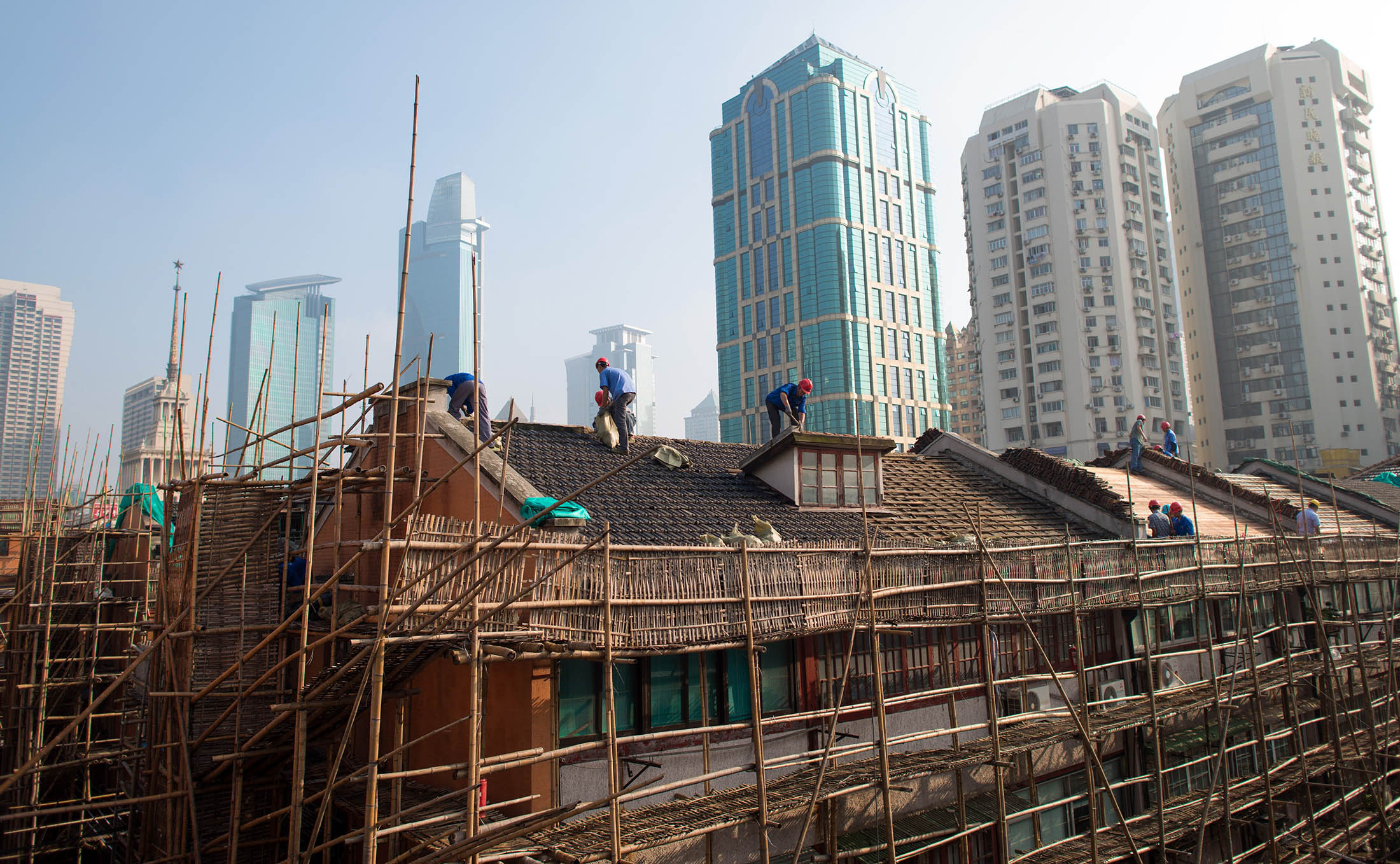 Labourers renovate a roof of a residential lane house in Shanghai on August 21, 2014. Foreign direct investment (FDI) into China dropped by more than a sixth year-on-year to a two-year low in July, the government said, but denied any link to Beijing's multiple probes into foreign companies. AFP PHOTO / JOHANNES EISELE (Photo credit should read JOHANNES EISELE/AFP/Getty Images)
