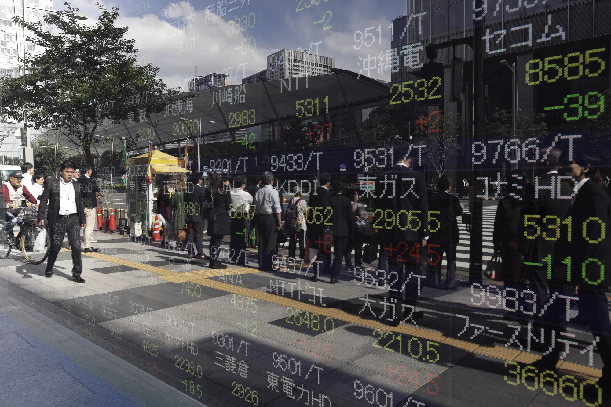 Pedestrians are reflected in an electronic stock board outside a securities firm in Tokyo, Japan.