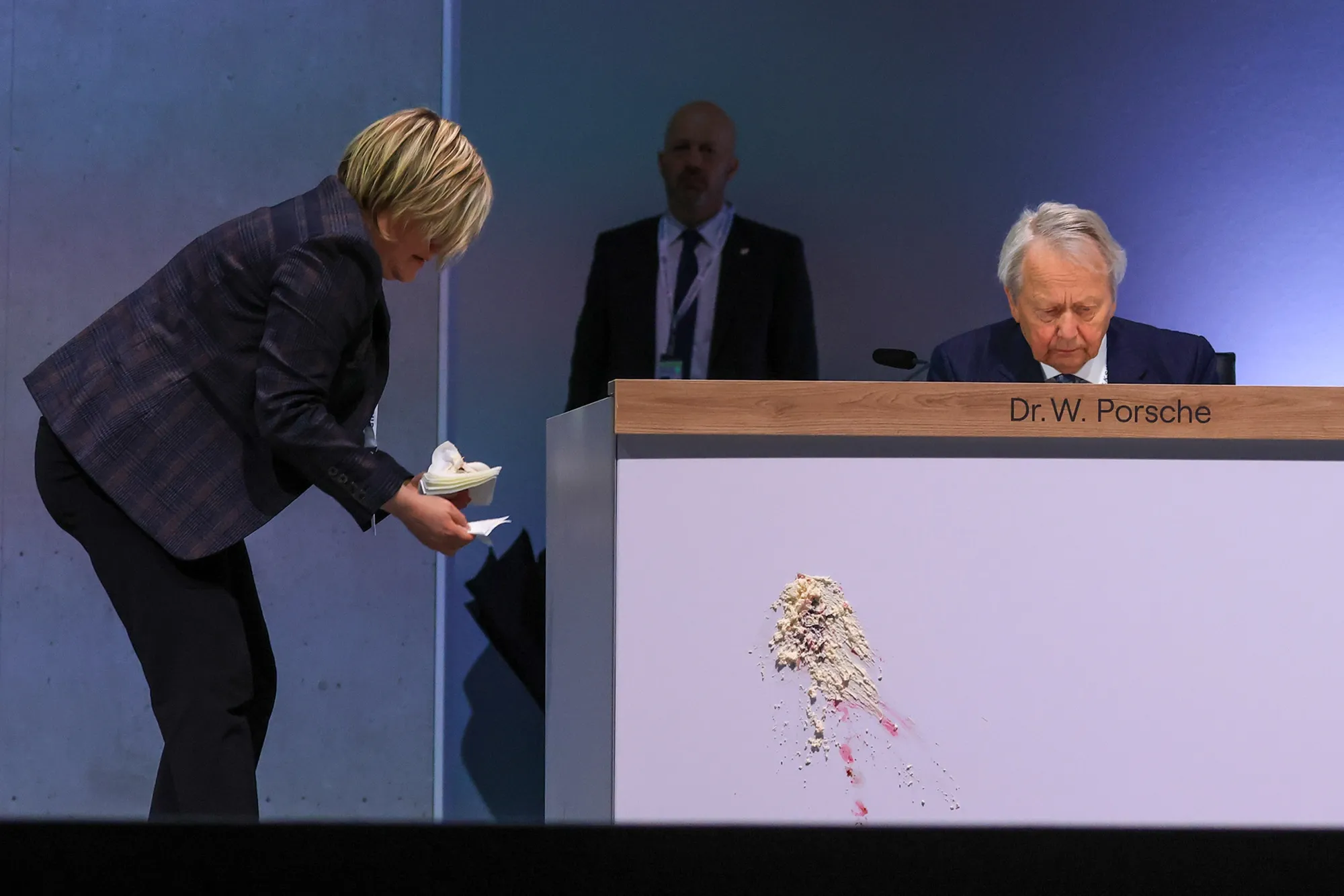 A worker cleans up cake thrown by a protester near Wolfgang Porsche at the Volkswagen AG AGM in Berlin, on May 10.