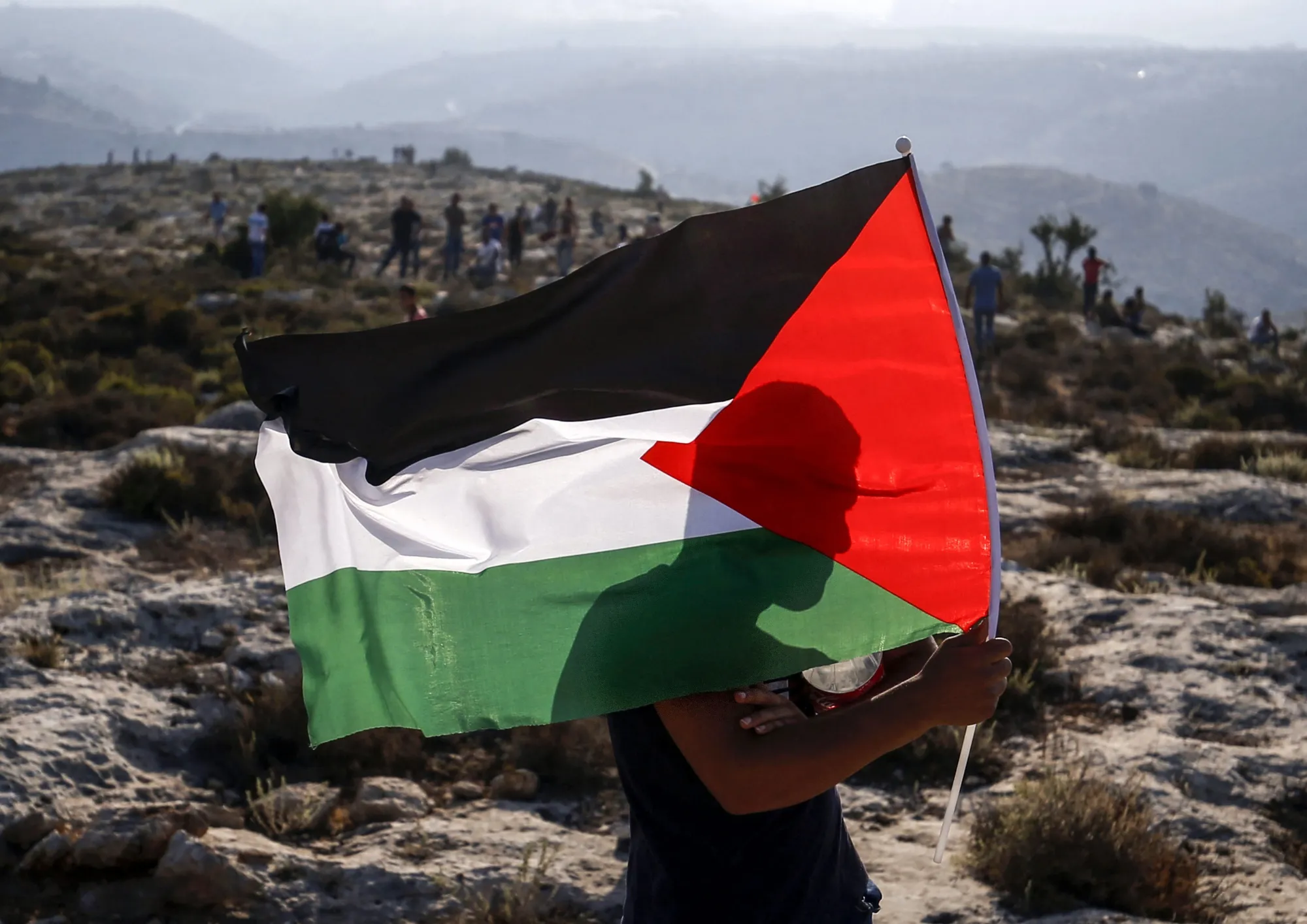 A man waves a Palestinian flag&nbsp;in Ras Karkar.