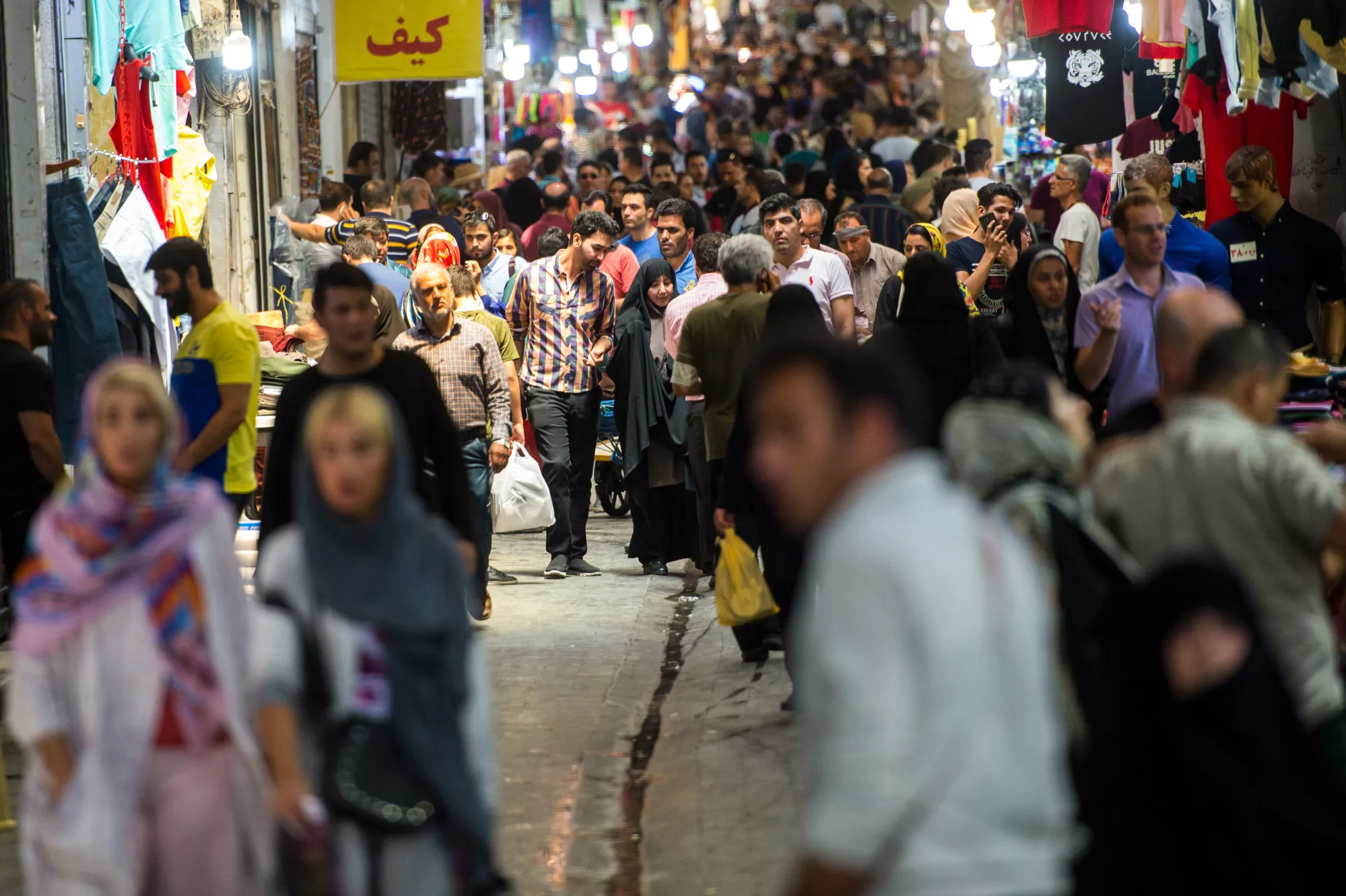 Visitors walk through an arcade lined with stores inside the Grand Bazaar in Tehran/