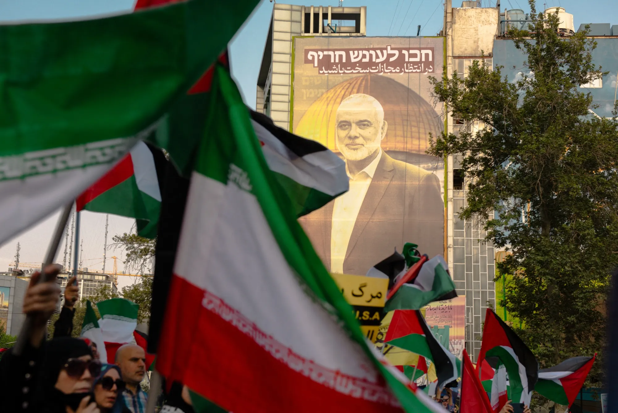 Iranians wave flags while attending a demonstration denouncing the killing of Ismail Haniyeh at Palestine Square in Tehran on July 31.