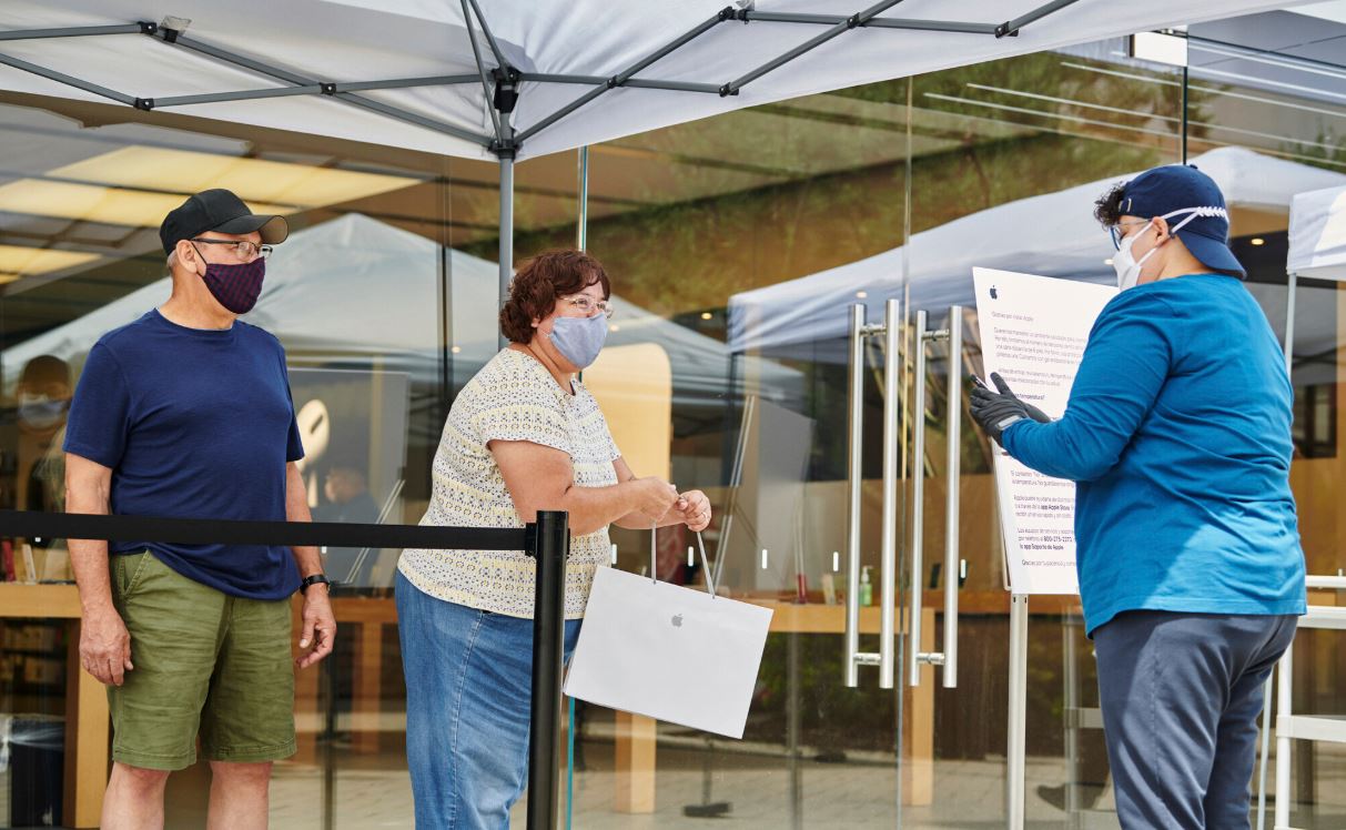 A worker assists customers outside an Apple store.&nbsp;