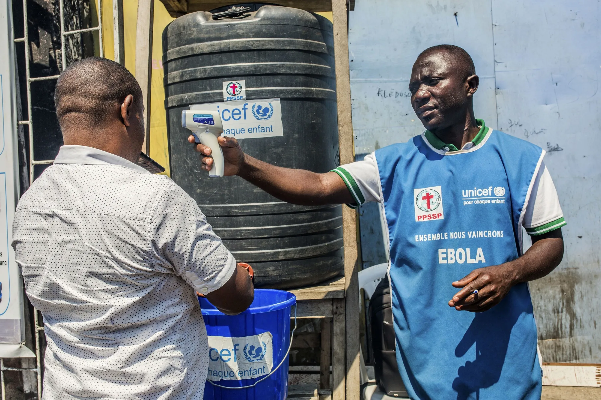 A man washes his hands with chlorine as a Unicef health worker takes his temperature at a washing station in Goma, in 2019.