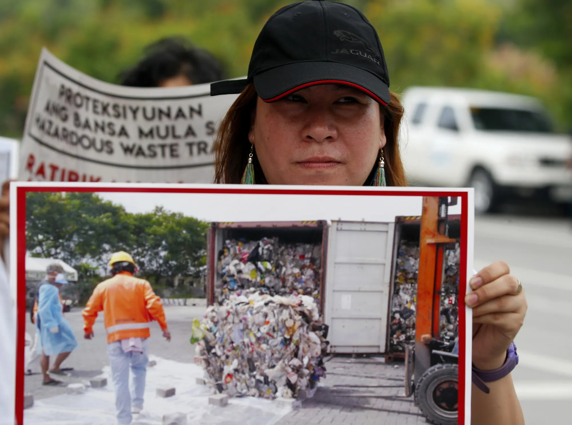 An environmentalist holds a photo of a container of garbage from Canada near Manila on May 24.