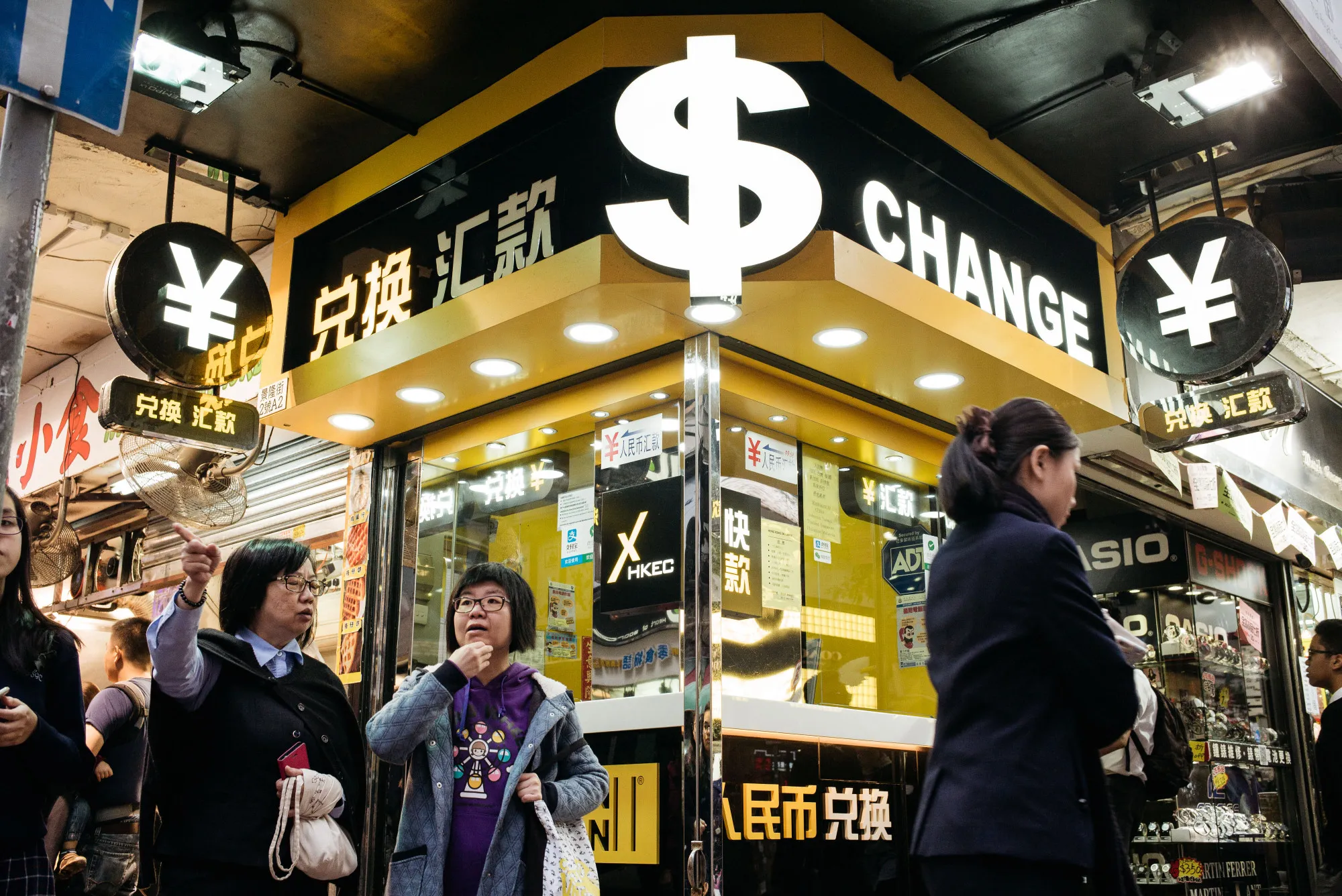 Pedestrians walk past a currency exchange store in Hong Kong, China, in March 2017. Money is increasingly being transferred online.