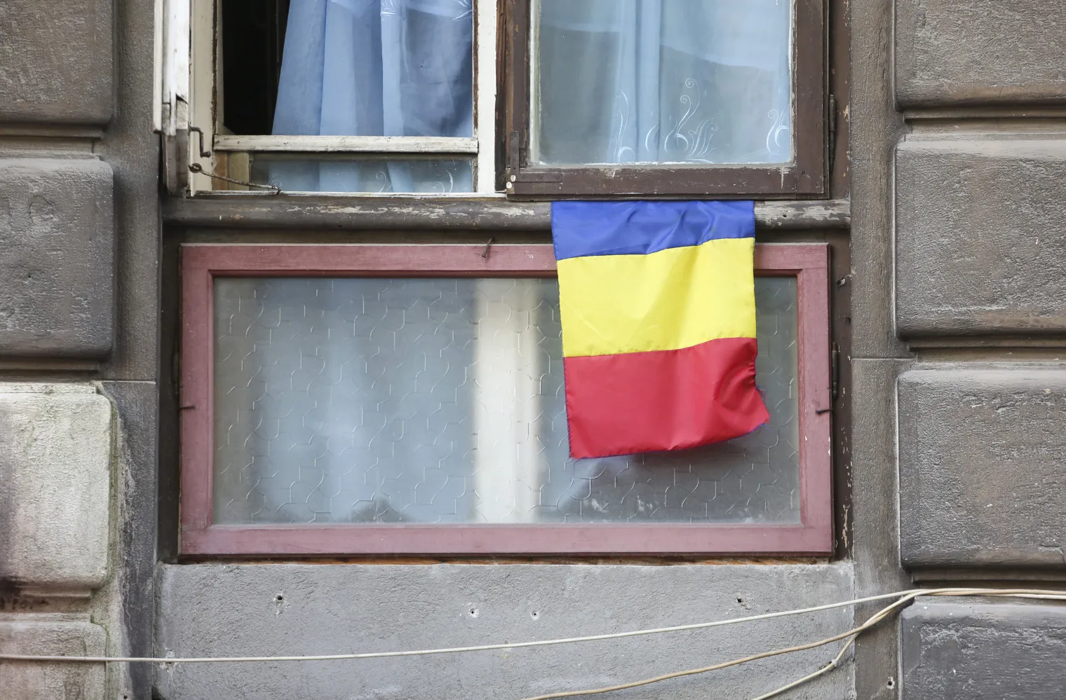 The Romanian national flag is seen hanging from a window of a residential apartment in the center of Bucharest, Romania, on Wednesday, July 2, 2014. Romania's economy grew 3.8 percent from a year earlier in the first quarter, boosted by industry and exports.