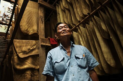 Farmer Winai Chaikunanant stands next to rubber sheets in a drying room