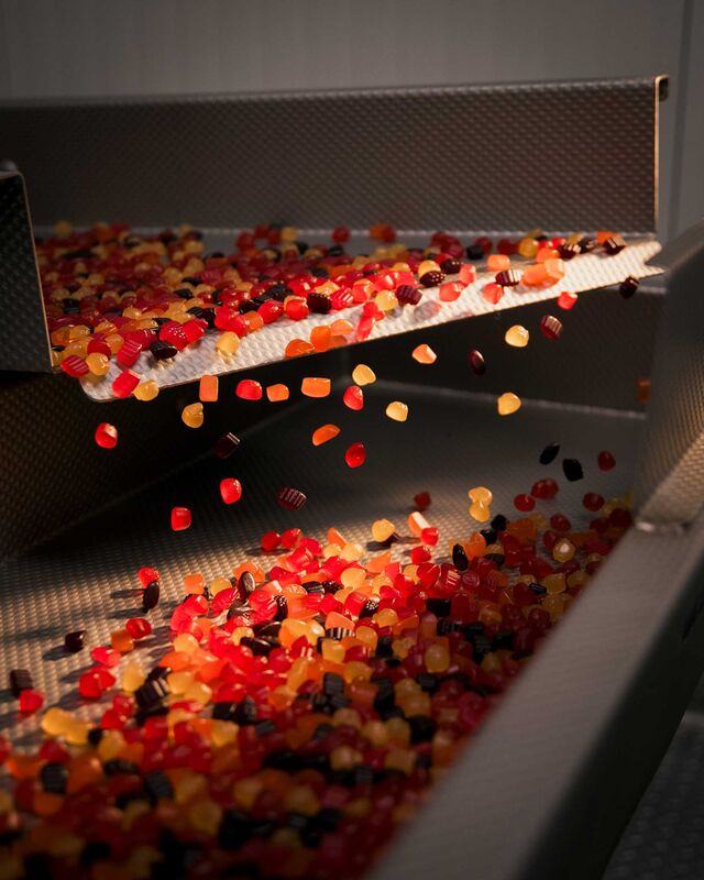 Freshly glazed snacks feed out of the polishing drum.