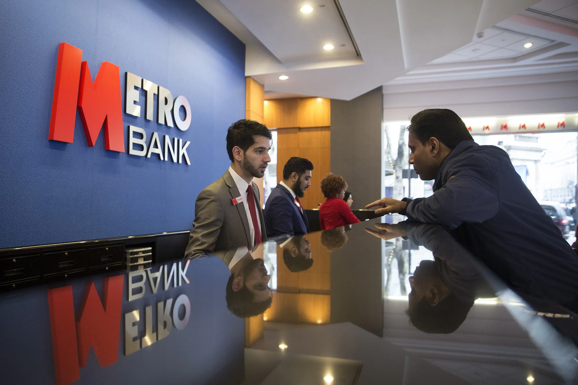 An employee serves a customer inside a branch of Metro Bank Plc in London, U.K.