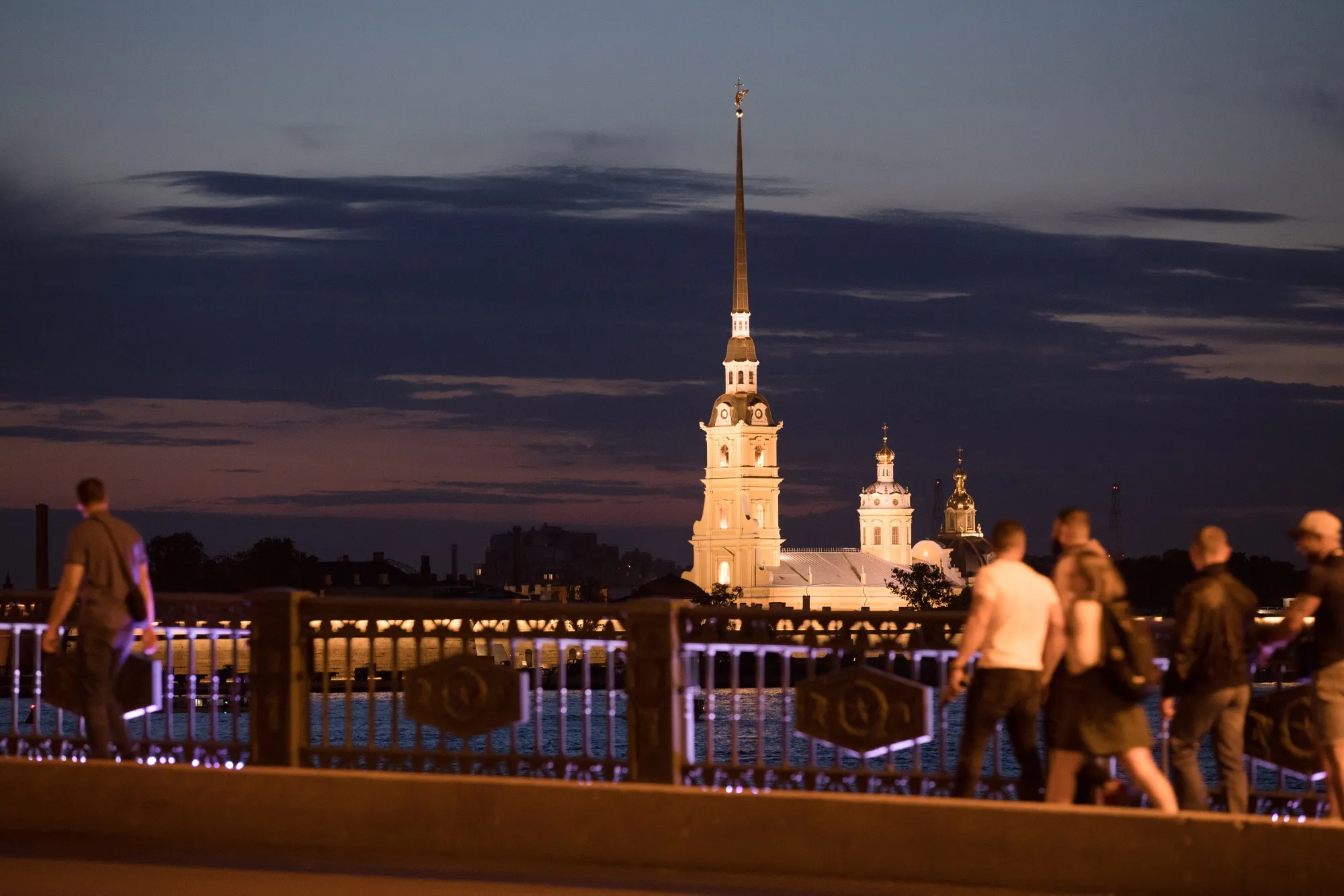 Pedestrians walk beside the River Neva past the Peter and Paul Fortress in St. Petersburg.