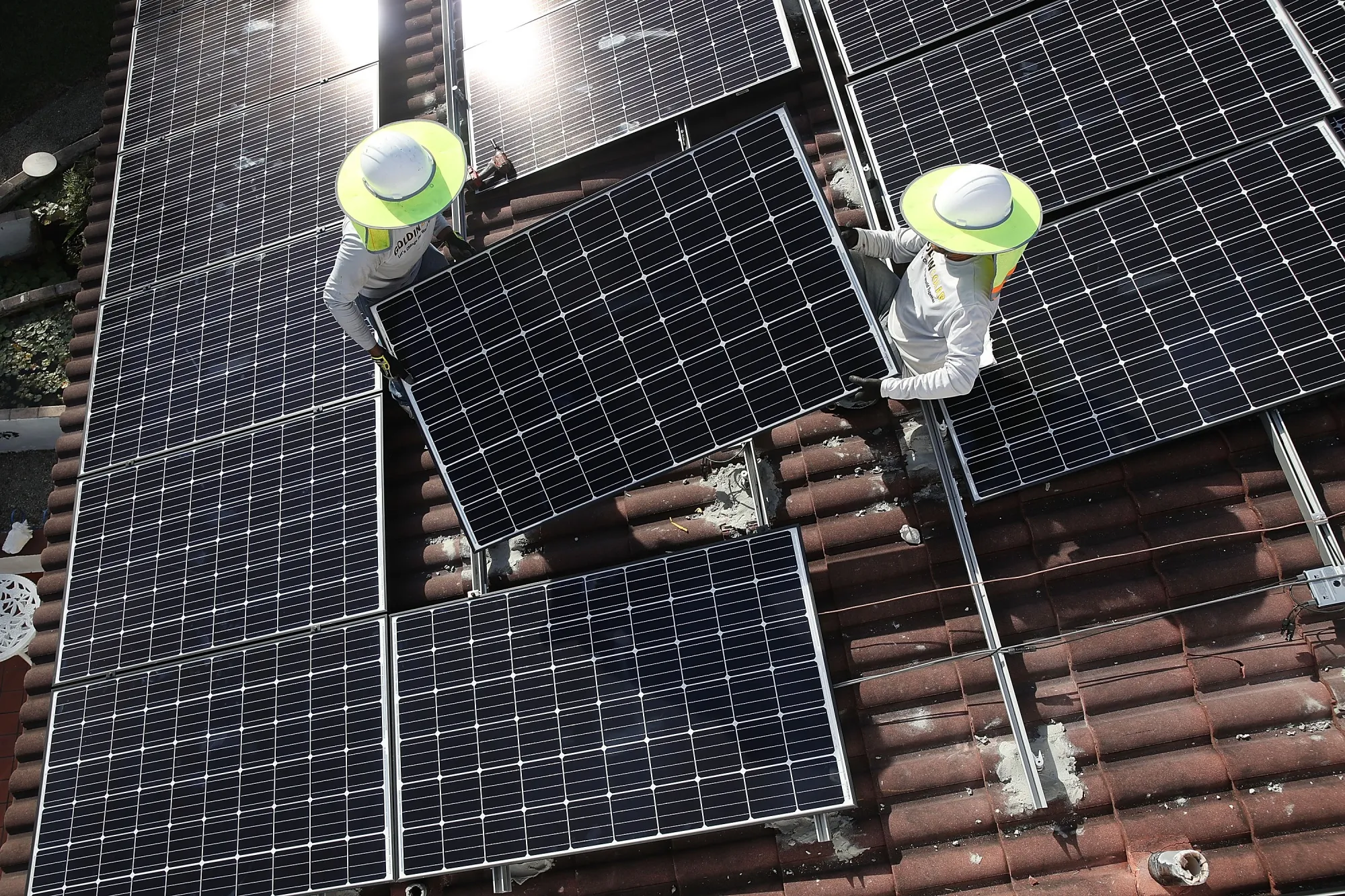 Workers install a solar panel system on the roof of a home in Palmetto Bay, Florida, in 2018.