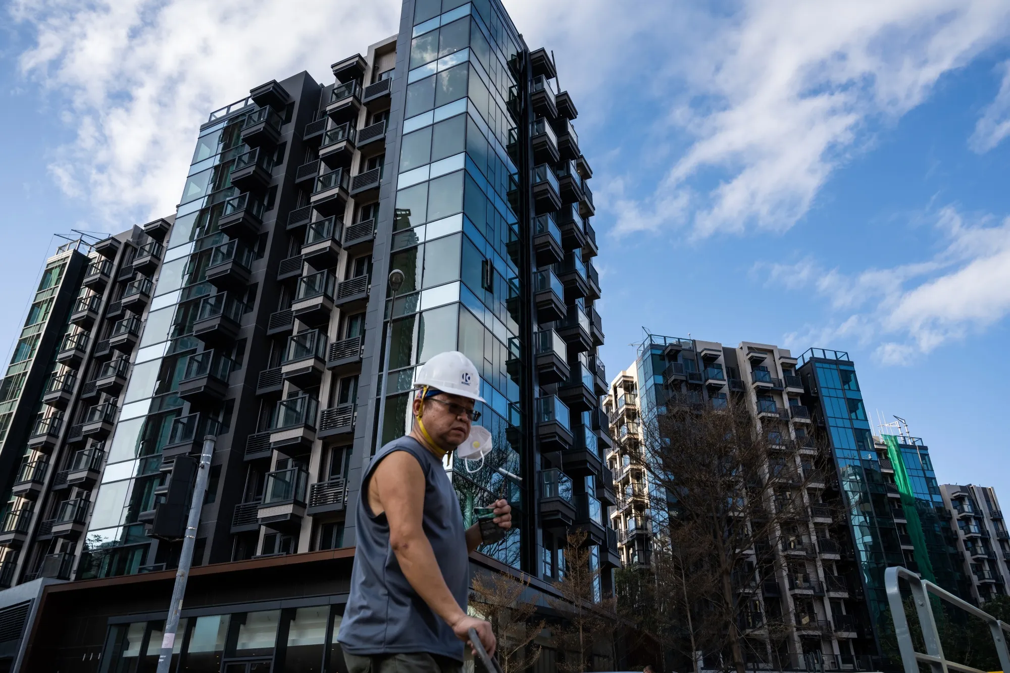 A worker walks past residential buildings at the Wetland Seasons Park project&nbsp;in the Tin Shui Wai area of Hong Kong, China, on Jan. 31.