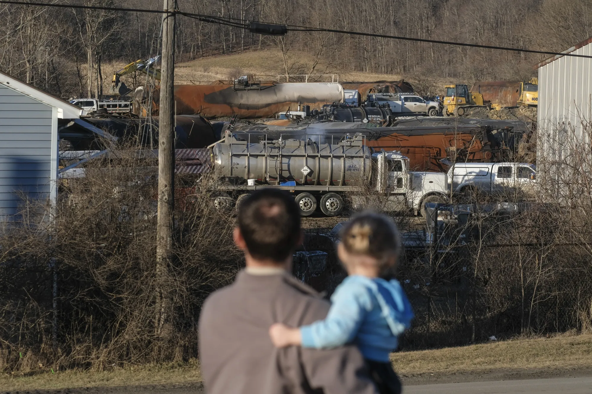 A family inspects the wreckage of the Norfolk Southern train derailment in East Palestine, Ohio on Feb. 19.