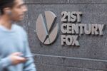A pedestrian passes in front of signage displayed outside Twenty-First Century Fox Inc. headquarters in New York, U.S.