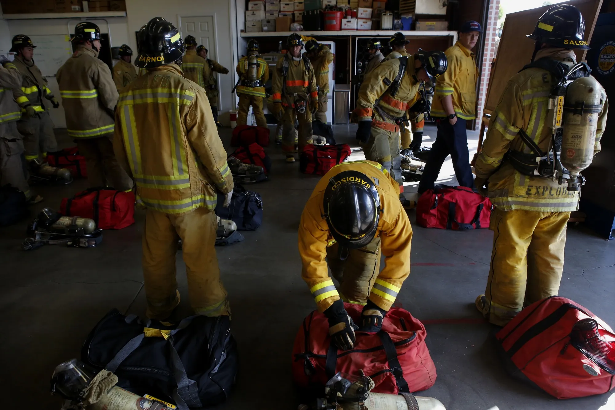 Fire academy recruits put on turnout gear and self-contained breathing apparatus before a training exercise.&nbsp;