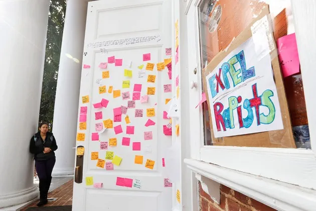 A University of Virginia student looks over postings on the door of Peabody Hall related to the Phi Kappa Psi gang rape allegations at the school.