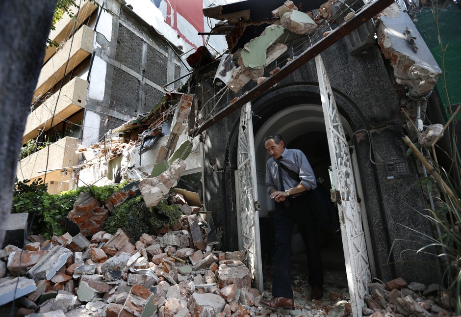A man walks out of the door frame of a building that collapsed after an earthquake, in the Condesa neighborhood of Mexico City, Tuesday, September 19, 2017.
